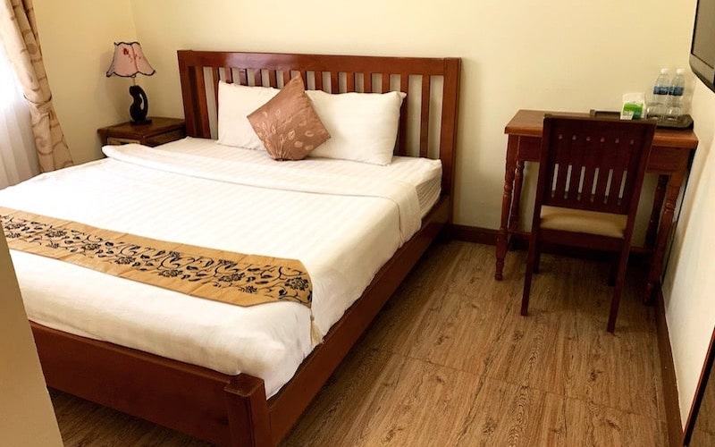 Standard room with a double bed, desk and wooden floor